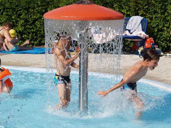 Sommerbad- Kinder haben unter einem Wasserspiel Spa&szlig;