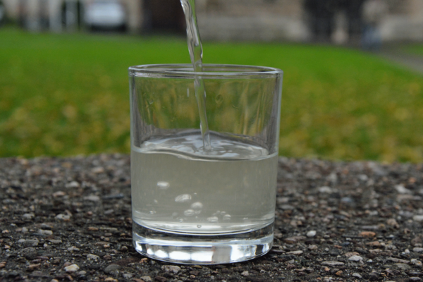 Gefülltes Glas mit Brakeler Brunnenwasser, das an der Außenzapfstelle der Trinkhalle "Am Kaiserbrunnen" erhältlich ist