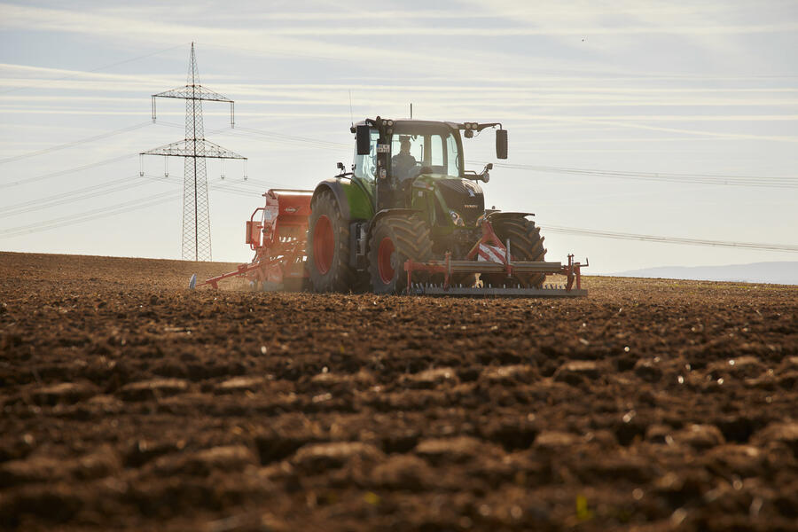 Auf dem Bild ist ein Traktor bei der Arbeit auf dem Feld zu sehen.