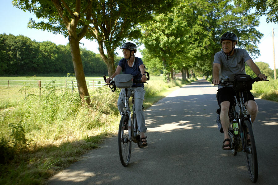 Ehepaar mit Fahrrädern auf einem Brakeler Fahrradweg in wunderschöner Brakeler Landschaft bei Sonnenschein