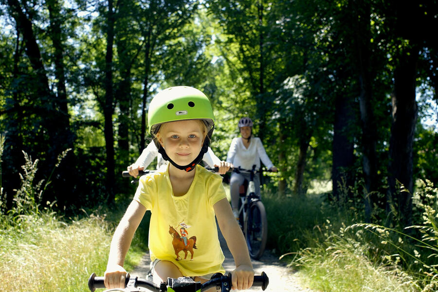 Glücklich lächelndes kleines Mädchen mit Fahrradhelm beim Radfahren