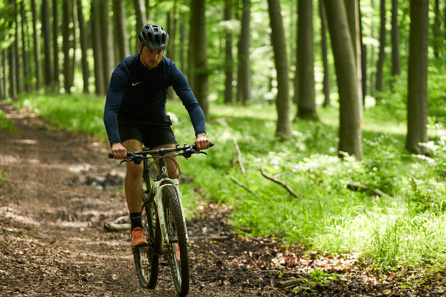 Sportlicher junger Mann mit Mountainbike im Wald