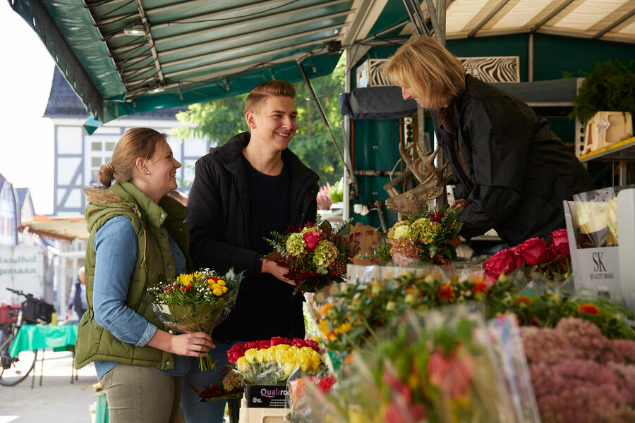 Junge Leute kaufen am Blumenstand auf dem Brakeler Wochenmarkt ein