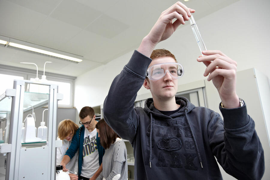 Ein Schüler schaut prüfend in ein Reagenzglas