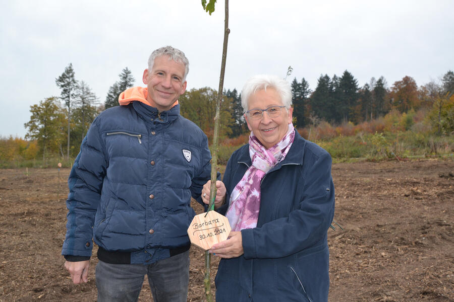 Das Bild zeigt Barabara und Bernd Krome aus Brakel, die gemeinsam einen Baum gepflanzt haben und nun ihr Baumschild aufhängen